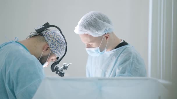 Chirurgové provádějí operaci na osobě v anestezii. Akce. Dva profesionální chirurgové provádějí operaci s jistotou a soustředěním. Operace osoby v anestezii v nemocnici — Stock video