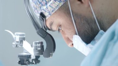 Operasyondaki profesyonel cerrahın yüzü. Başla. Anestezi altındaki kişinin ameliyatına odaklanmış bir cerrah. Cerrah operasyonu özgüven ve konsantrasyonla gerçekleştirir.