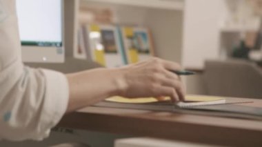 Kadın öğretmen, sınıftaki bir masada rafların kitaplarıyla ödevlerini kontrol ediyor. Stok görüntüleri. Kağıt bir defterin sayfalarını çeviren bir kalemle kadın ellerini kapat ve not al..