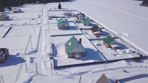 Piękne ekologiczne miejsce do życia na wsi. Klip. Widok z lotu ptaka na małe domki i zaśnieżone pole w zimowy dzień. — Wideo stockowe
