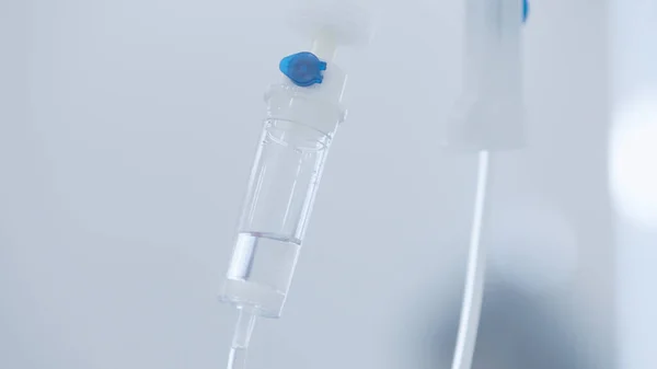 Primer plano del tubo intravenoso. Acción. Gotero con droga goteando lentamente por el tubo. Tubos IV para el paciente enfermo después de la cirugía — Foto de Stock