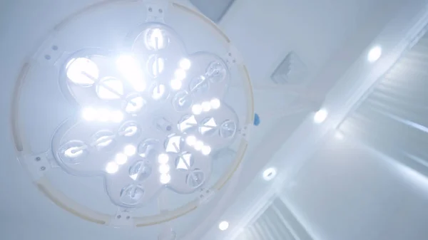 Bright surgical lamp light. Action. Blinding light of big lamp in operating room. Operating lamp is blinding with bright light during anesthesia