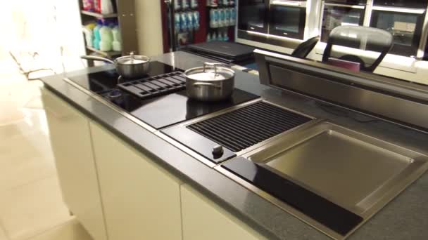 Échantillon de cuisine moderne au magasin. Des ustensiles de maison. Intérieur d'une nouvelle cuisine avec racks, casseroles en acier sur la plaque à induction au grand magasin. — Video