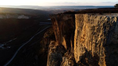 Yazın yüksek kayalıklardan oluşan etkileyici bir hava manzarası. Vuruldu. Arka planda dağlık vadi olan yeşil bitkilerle kaplı vahşi kaya oluşumlarıyla doğal manzara..