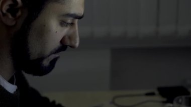 Akşam geç saatlerde ofiste dizüstü bilgisayarı olan düşünceli bir iş adamı, işkolizm kavramı. HDR. Ciddi düşünceli bir adam bilgisayarının ekranına bakıyor ve daktilo yazıyor..
