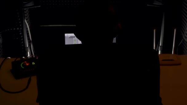 Zadní pohled mužského zvukaře pracujícího v hudebním nahrávacím studiu před počítačem. HDR. Tvůrce hudby při práci v temném studiu. — Stock video