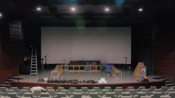 Muitas pessoas preparando o palco para uma apresentação. Vídeo. Instalação de decorações para a peça no salão de teatro. — Vídeo de Stock