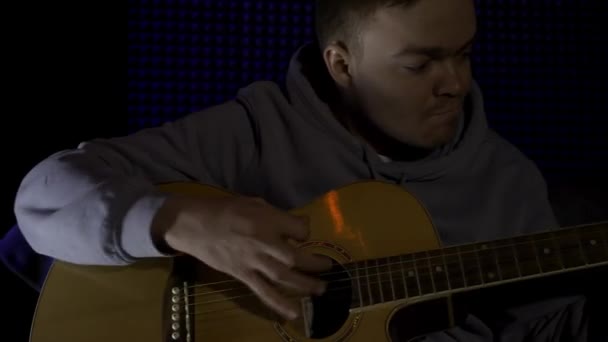 Gitar çalan adam, profesyonel ses stüdyosunda şarkı kaydediyor. HDR. Karanlık bir odada akustik gitar çalan genç bir adamın portresi.. — Stok video