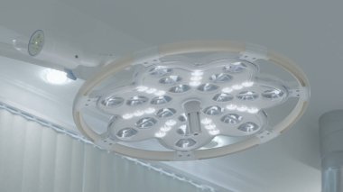 Parlak ışığı olan bir ameliyat lambası. Başla. Parlak beyaz ışıklı modern ameliyathane lambası. Ameliyathanede, yuvarlak cerrahi lambayla aydınlatma.