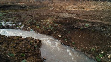 İlkbaharın başlarında tarladan akan bir dere. Vuruldu. Dar, hızlı bükülen bir nehir ve nadir yetişen yeşilliklerle dolu taşlık bir arazinin havadan görünüşü..