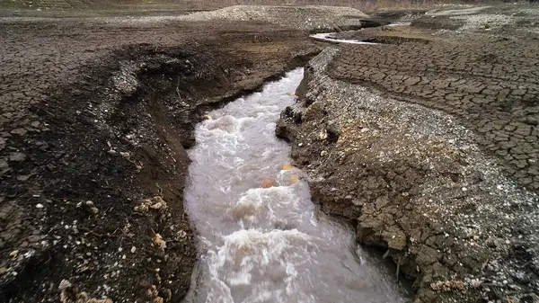 狭い川の流れと乾燥した地面を分割します。撃たれた。亀裂や冷たい流れの速い流れとフィールドと秋の風景. — ストック写真