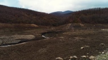 Kurumuş bir tarla ve tepelerin havadan görünüşü. Vuruldu. Kuru çimenlerin ve bulutlu arka planda sarı çalıların sonbahar doğal manzarası.