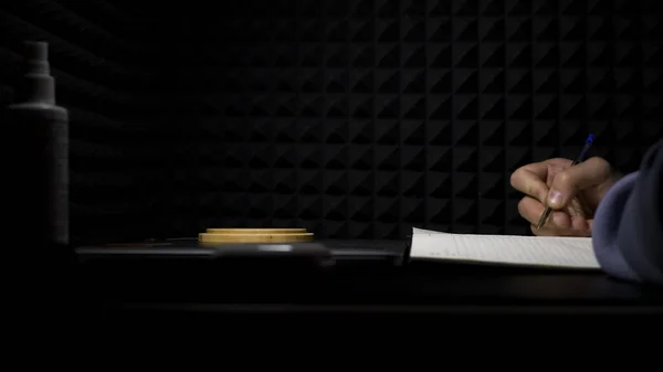 Concetto di songwriting, vista laterale di un uomo che scrive testi in uno studio di musica professionale. HDR. Processo di creazione di una canzone da parte dell'autore, musicista scrittura di testo su un foglio di carta. — Foto Stock
