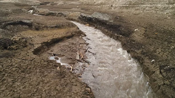 Vue aérienne d'un sol profondément fissuré et d'un petit ruisseau. Fusillade. Concept de climat sec, écologie et invasion du désert. — Photo