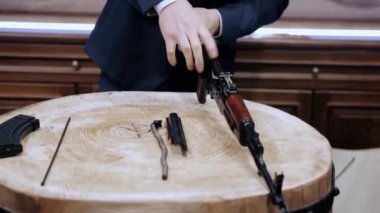 Kalaşnikof tüfeğinin montajı. Video kaydı. Özel etkinlik sırasında resmi kıyafetli bir adamın otomatik silahı monte edişinin yakın çekimi..