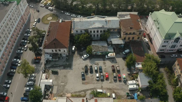 Aerial view of a city yard with ugly facades of houses and many parked cars. Stock footage. Parking located by the abandoned old houses and administrative building. — Stock Photo, Image