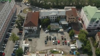 Bir şehir avlusunun havadan görünüşü. Çirkin yüzlü evler ve park etmiş bir sürü araba. Stok görüntüleri. Terk edilmiş eski evlerin ve idari binaların yanında park yeri.