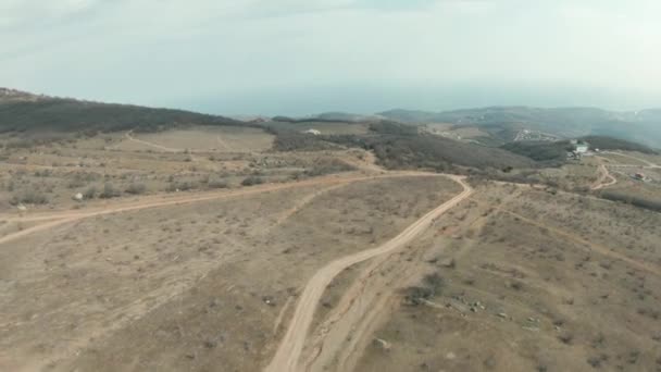 Veduta panoramica aerea di una pittoresca valle collinare asciutta circondata da un paesaggio montano canadese. Gli hanno sparato. Concetto di viaggiare, sorvolando stretti sentieri su campi con montagne nebbiose sullo sfondo. — Video Stock