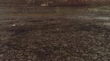 Kurumuş bir gölün dibinin havadan görünüşü, küresel ısınma ve iklim felaketi kavramı. Vuruldu. Derin çatlakları olan kuru kahverengi toprak..