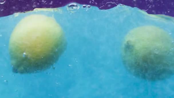 Les citrons tombent dans l'eau bleue. Images d'archives. Citrons entiers éclaboussent dans l'eau bleu vif. Citrons tombent dans l'eau bleue avec des étincelles — Video