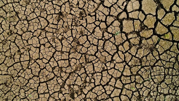 Bovenaanzicht vanuit de lucht op de grond tijdens het droge seizoen. Neergeschoten. Droogte concept, diepe scheuren in de bodem, gebrek aan vocht. — Stockfoto