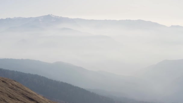 Vista aérea de majestuosas montañas cubiertas de espesa niebla temprano en la mañana bajo los rayos del sol. HDR. Volando por encima de hermosas colinas tranquilas. — Vídeos de Stock