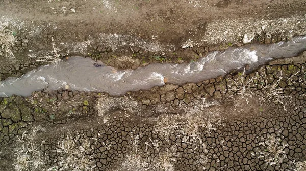 Aerial over a narrow stream with strong current on dry land. Shot. Wide river became a water brook because of drought, concept of ecology. — Stock Photo, Image