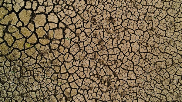 Vista aérea superior del suelo durante la estación seca. Le dispararon. Concepto de sequía, grietas profundas en el suelo, falta de humedad. — Foto de Stock