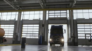 Bir servis merkezinin garajına giren büyük mavi bir kamyon. Sahne. Araç bakımı konsepti, servis istasyonuna giren kamyon makinesi.