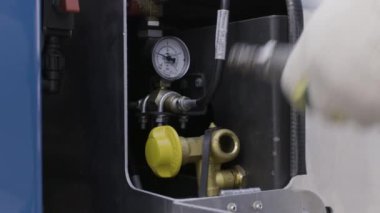 Lastikleri şişirmek için yeni bir kompresör kullanan koruyucu eldivenli işçi ellerini kapat. Sahne. Bir hizmet merkezinin atölyesinde profesyonel ekipman..