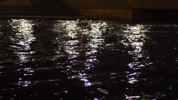 A luz de lanternas reflete-se no canal de cidade à noite. Imagens de stock. A luz da cidade noturna reflete-se em águas do canal de cidade. Águas escuras de canais de cidade com reflexão de luz de rua — Vídeo de Stock