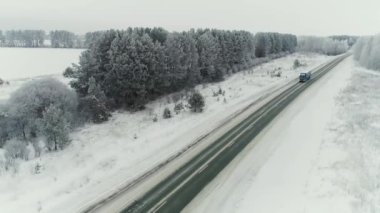 Açık bir kış gününde bir demiryolu boyunca giden bir B yük kamyonunun hava görüntüsü. Kargo kamyonları Utah 'taki engebeli karlı çölde konteynır taşıyorlar..