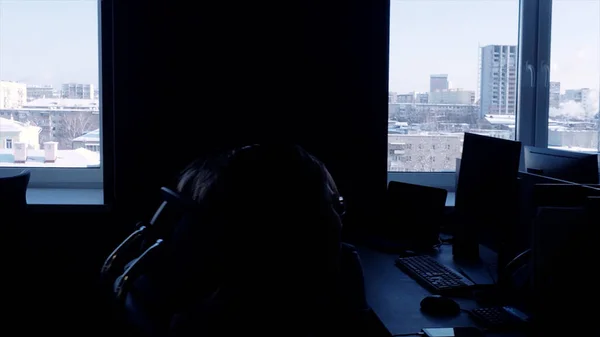 Wczesnym rankiem w call center z pracownikami wykonującymi telefony. Odbiór. Ciemne biuro z urzędnikami siedzącymi przy biurkach przy oknach. — Zdjęcie stockowe