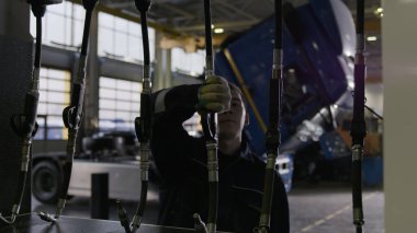 Profesyonel bir tamircinin kamyon tamiri için İngiliz anahtarı kullandığına dair arka görüş. Sahne. Bir hizmet merkezinin ayrıntıları veya çalışma süreci.