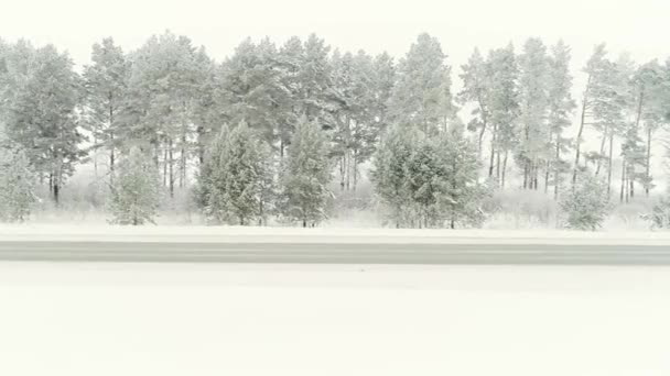 Foto aérea de carretera cubierta de nieve en el campo Montañas Cárpatos con coche en camino. Escanear. Resbaladizo camino de campo de invierno con puente sobre el río congelado. Karelia, Rusia. Vehículos que circulan — Vídeos de Stock