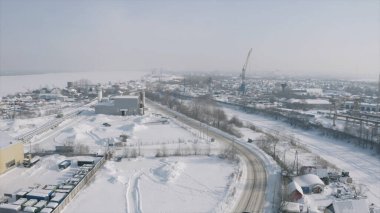 Kış günü karla kaplı küçük bir kasabanın havadan görünüşü. Şarjör. Şehrin sanayi bölgesi, küçük binaları olan bir inşaat alanı..