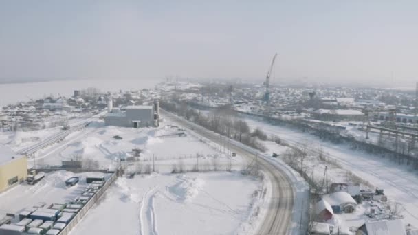 Légi felvétel egy téli napon havazott kisvárosról. Csípés. A város ipari negyede, kis épületekkel rendelkező építési terület. — Stock videók