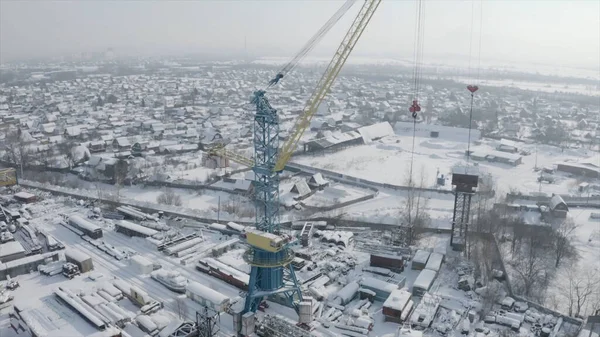Luchtfoto van de bouwplaats van de stad met een kraan op een besneeuwde winterdag. Een knip. Industriële zone van een grote stad en het gebouw daken bedekt met witte sneeuw. — Stockfoto