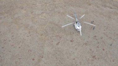 Kuru zemindeki helikopterin havadan görüntüsü küçük bir grup insanı kurtarmak için geldi. Şarjör. Vahşi doğada kaybolmuş turistleri kurtarmak.