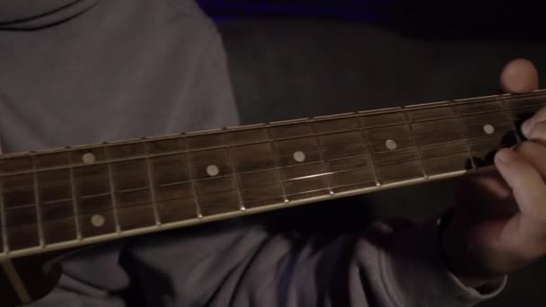 Close-up de homem tocando guitarra. HDR. O homem toca violão simples em casa. Jovem toca guitarra na semi-escuridão — Vídeo de Stock