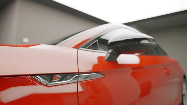 Κοντινό πλάνο του πλευρικού καθρέφτη και μια πόρτα ενός νέου κόκκινου αγωνιστικού αυτοκινήτου σταθμευμένο στο γκαράζ. Πάμε. Όμορφο καθαρό και λαμπερό ακριβό αυτοκίνητο. — Φωτογραφία Αρχείου