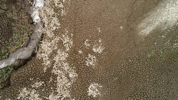 Vue aérienne d'un fond de lac sec avec un sol profondément fissuré et une petite source d'eau. Vidéo. Texture inhabituelle avec de nombreuses fissures dans le sol, concept de changement climatique et réchauffement climatique. — Photo