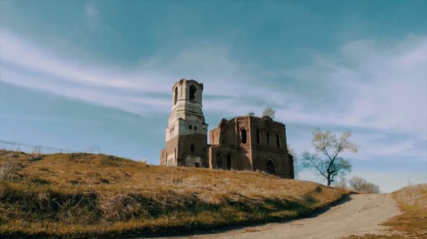 Uma igreja de pedra antiga que constrói no fundo azul do céu nublado. Vídeo. Vista inferior de um edifício velho tijolo vermelho e árvores de outono e um prado. — Fotografia de Stock
