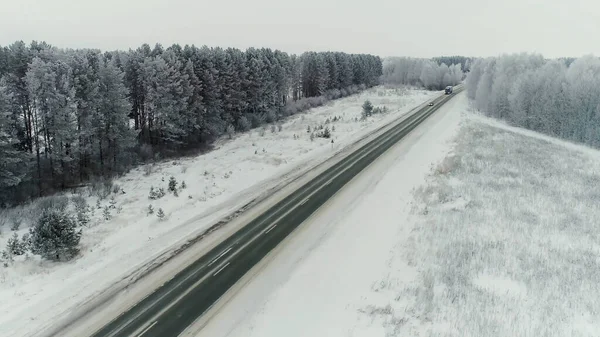 Widok z powietrza na ciężarówkę z ładunkiem B jadącą autostradą biegnącą wzdłuż linii kolejowej w pogodny zimowy dzień. Samochody ciężarowe kontenery transportowe przez pustynię śnieżną w Utah. — Zdjęcie stockowe