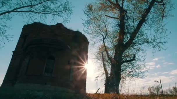 Ein altes steinernes Kirchengebäude auf blauem bewölkten Himmel. Video. Blick von unten auf ein rotes Backsteingebäude und Herbstbäume. — Stockvideo