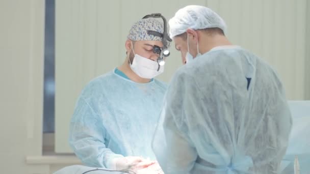 Operaci provádějí dva profesionální lékaři v lékařských maskách a čisté uniformě. Akce. Koncepce zdravotní péče a medicíny. — Stock video