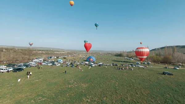 Globos de aire caliente se elevan en el cielo durante el festival internacional de globos de aire caliente. Le dispararon. Hermosos aerostatos se elevan por encima del prado verde. — Foto de Stock