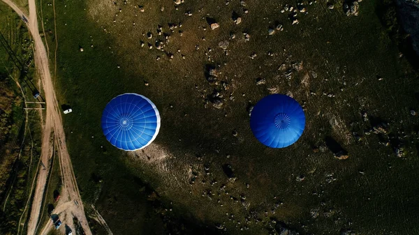 Vue de dessus de deux montgolfières colorées dans la campagne. Fusillade. Aérostat vol au-dessus des champs et des pierres, concept d'aventure. — Photo