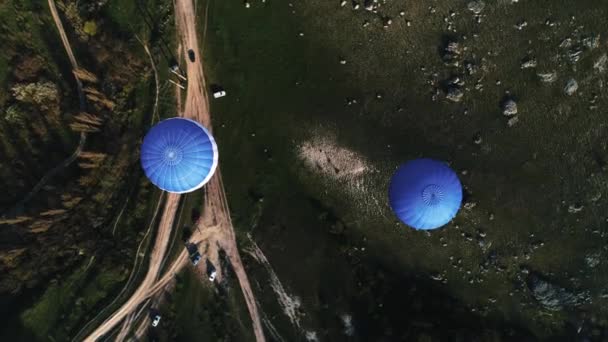 Luftaufnahme von zwei blauen Heißluftballons, die über ländlichen Straßen und grünen Bäumen und Feldern fliegen. Schuss. Fliegen im Himmel über der grünen Natur. — Stockvideo