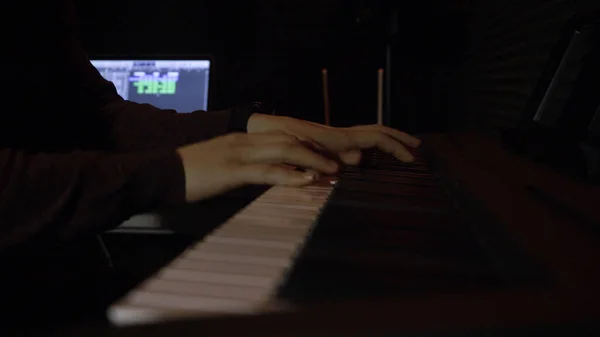 Man spelar piano i mörker. HDR. Manliga händer spelar pjäs på elektroniskt piano i mörka rummet. Musiker spelar piano ensam i mörk studio — Stockfoto